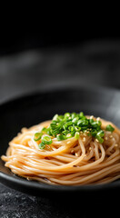 A bowl of soba noodles topped with chopped vegetables and seaweed in a savory broth, presented elegantly on a minimalistic black background.