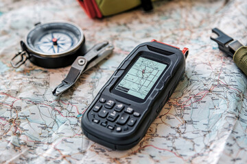 GPS device on a map with a compass and tools, illustrating outdoor navigation essentials for adventure and exploration in unknown territories.