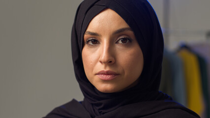 Serious irritated Muslim woman girl wearing hijab in studio adjusting traditional scarf Islamic lady fixing clothes displeased Arabian model sigh strict annoyed gaze female looking at camera portrait