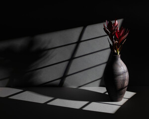 Elegant ceramic vase with red flowers in dramatic lighting