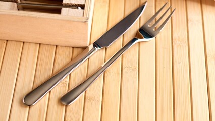 Silver knife and fork placed neatly on wooden surface, emphasizing sleek design and minimalist aesthetic. with Knife and fork materials highlights eco-conscious dining choices Minimalistic design