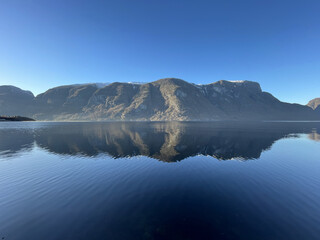 Beautiful cold and blue Fjord in Norway with Reflections of nearby Mountains