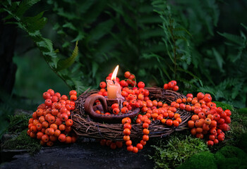 candlestick with candle and rowan tree berries in forest. Magic, Witchcraft, protective rowanberry...