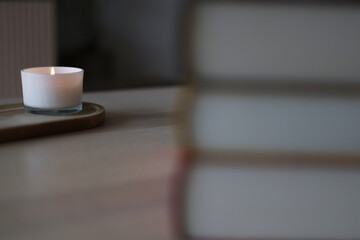 Books stacked to the right, their secrets sealed, as the candle's light flickers softly in the stillness