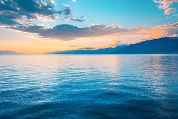 Obraz premium Tranquil Sunset over Calm Ocean Water with Mountain Range in Distance