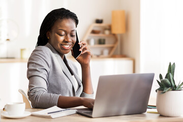 African American Businesswoman Talking On Cellphone And Using Laptop In Modern Office