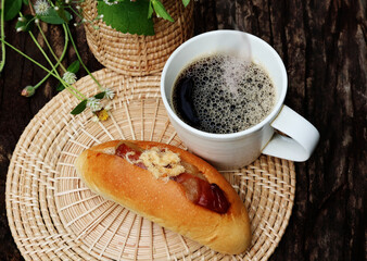Hot black coffee paired with stuffed bread On a stand made of light colored wood. Decorated with white grass flowers outdoor dark wood table

