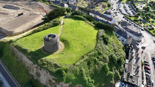 Aerial of Howth Castle with Martello Tower on a hilltop surrounded by the city buildings and marina