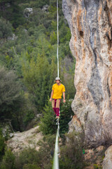 A tightrope walker walks along a cable stretched over a canyon.