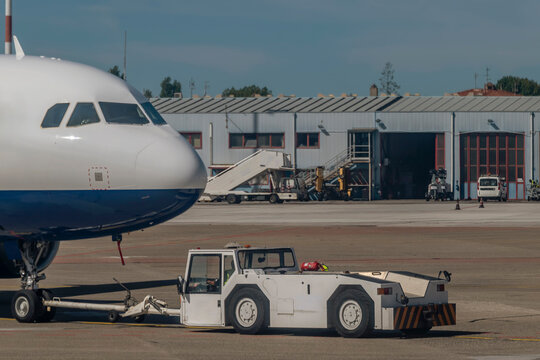 A white pushback tug pushes a plane inside the airport, Pisa, Italy