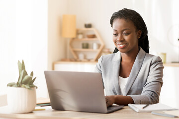 Female entrepreneur. Smiling african american businesswoman working on laptop in modern office, copy space