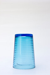 A blue glass cup in a face-down position, on a white background. This glass can be used to hold water and other liquids. Commonly used as cutlery.