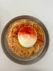 Spanish frittata, common dish in Spain made with eggs and potatoes.  Mayonnaise and paprika topping.  Served on a plate, then on a white background.  View from the top. 