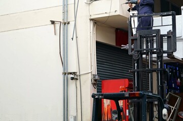 A technician is standing on a Forklift to use a drill to drill.