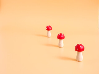 Three wooden fly agaric mushrooms on an orange background, Place for inscription. High quality photo