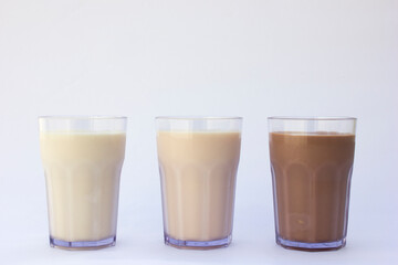Trio of Milk Flavors”: Three pristine glass tumblers stand side by side, each containing a distinct milk flavor. Strawberry, chocolate and original flavor.