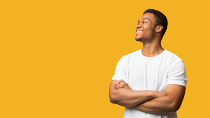 Full Of Joy. Happy african american guy looking aside at copyspace with crossed arms folded,...