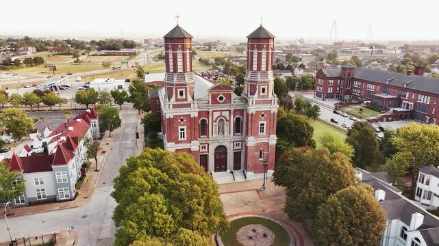 Panning around The Shrine of St. Joseph Catholic Cathedral Church in Downtown Saint Louis, Missouri with green trees and a neighborhood.
