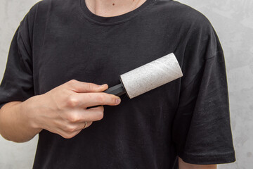 Man cleans black t-shirt with sticky roller. The fabric that everything sticks to