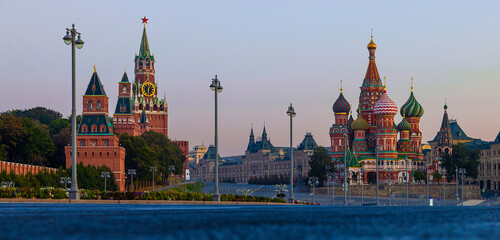 The iconic silhouettes of the Kremlin and St. Basil's Cathedra and Red Square are visible as twilight descends over Moscow. The domes and historic architecture create a mesmerizing view of the city.