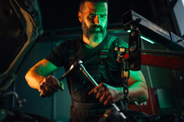 Mechanic in overalls working on an engine part with determination.