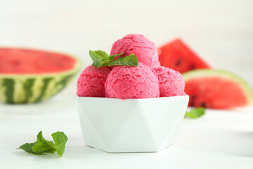 Scoops of tasty watermelon sorbet with mint in bowl on white table, closeup