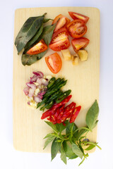 Fresh ingredients like tomatoes, garlic, and sliced chillies on a wooden cutting board, ready for cooking.