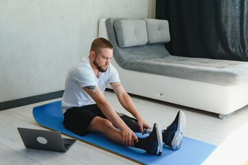 A man with a prosthetic leg does sports exercises on a mat at home. The concept of rehabilitation