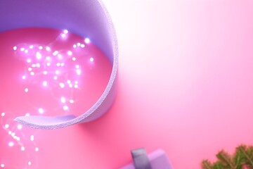 Yoga mat, block, Christmas lights and fir branches on pink background, flat lay. Space for text