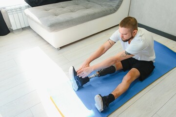man exercising online stretching his legs at home, with amputated leg prosthesis