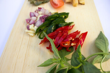 Fresh ingredients like tomatoes, garlic, and sliced chillies on a wooden cutting board, ready for cooking.