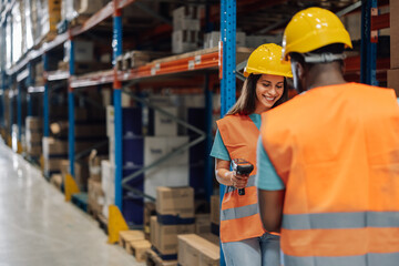 Diverse warehouse workers inspecting shelves with a barcode scanner.