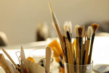 Ceramic tools and brushes arranged on table in pottery workshop