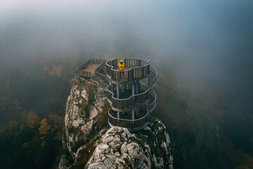 Drone takes aerial footage of the canyon during a foggy morning. A man watches the view from the...