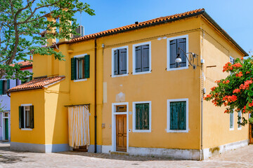 June 25, 2019. Italy. Burano. Italy. A Charming Yellow House Beautifully Surrounded by Lush Greenery and Colorful Flowers
