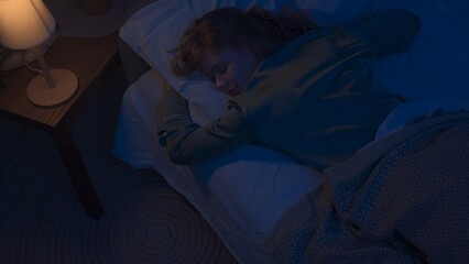 Woman in pajama sleeping in bed in dark apartment room, monster hiding under bed. Scary nighttime alone at home. Halloween horror concept. © kinomaster