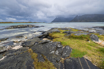 An overcast day in Gimsoy in the Lofoton Islands of Norway. There is a view of the ocean and mountains of this rugged landscape.