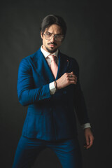 confident young businessman in navy blue suit posing in a cool way