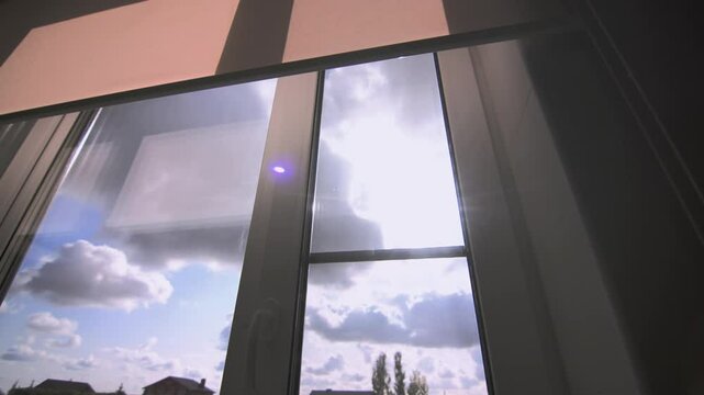 Sunbeam sparks through heavy clouds in sky out of office window. Gloomy cloudscape and bright sunlight view from school classroom