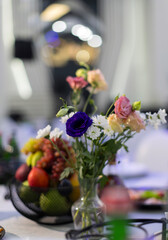 Elegant table setting with white roses in glass vases and a tall candle centerpiece