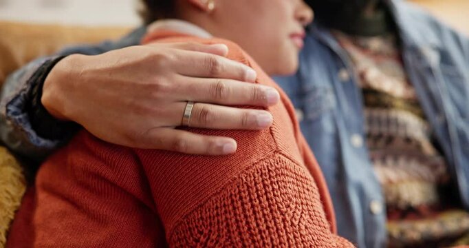 Hand, hug and couple on sofa in home with support, love and sympathy for mourning loss. Care, marriage and man embracing wife for connection with comfort, security or compassion in grief at house.