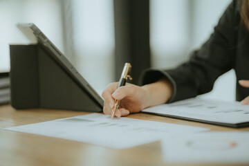Focused Businesswoman: A close-up photo of a woman's hand meticulously taking notes on a document,...