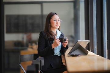 Businesswoman Taking a Break:  A professional woman in a suit takes a moment to relax with a cup of...