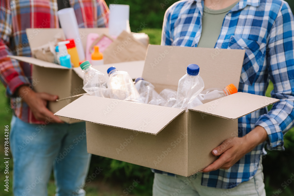 Wall mural Recycling. People holding cardboard boxes with different garbage outdoors, closeup