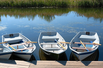 Fishing or tourist boats in calm river water. Wooden boats moored at the pier.