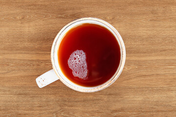 A cup of black tea on a wooden table close-up.
