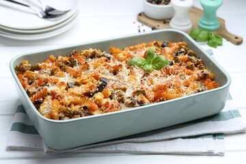 Delicious al forno pasta in baking dish on white wooden table