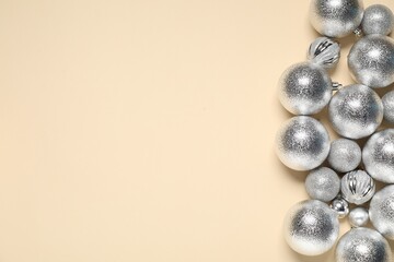 Shiny Christmas baubles on beige background, top view. Space for text