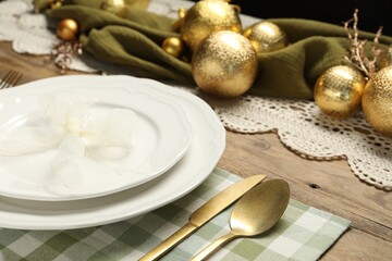Plates, cutlery and Christmas decor on wooden table, closeup