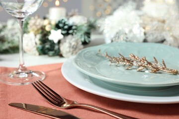 Christmas place setting with plates, cutlery and festive decor on table, closeup